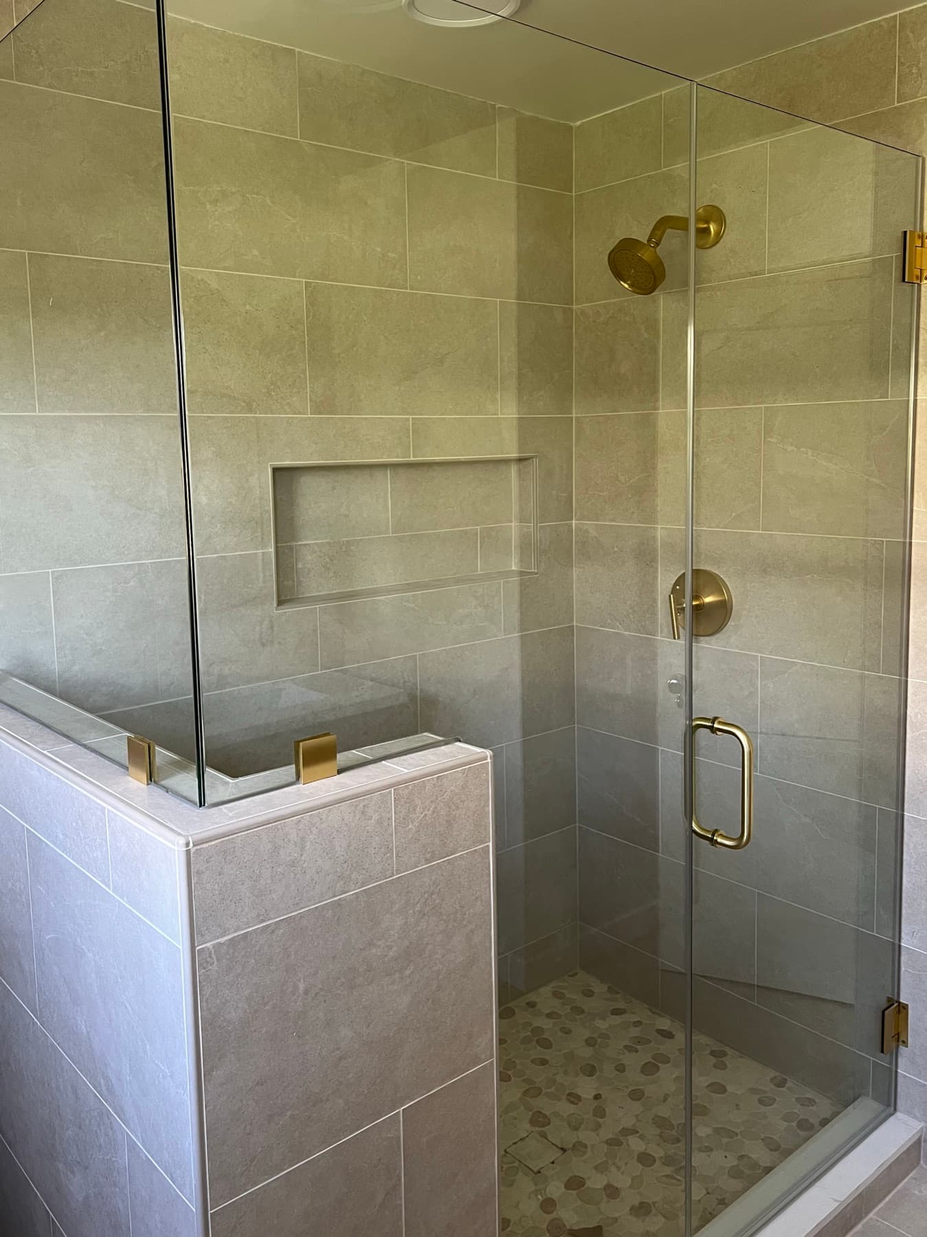 The half wall that replaced the old shower framing, capped and tiled so the glass sits on top of it.