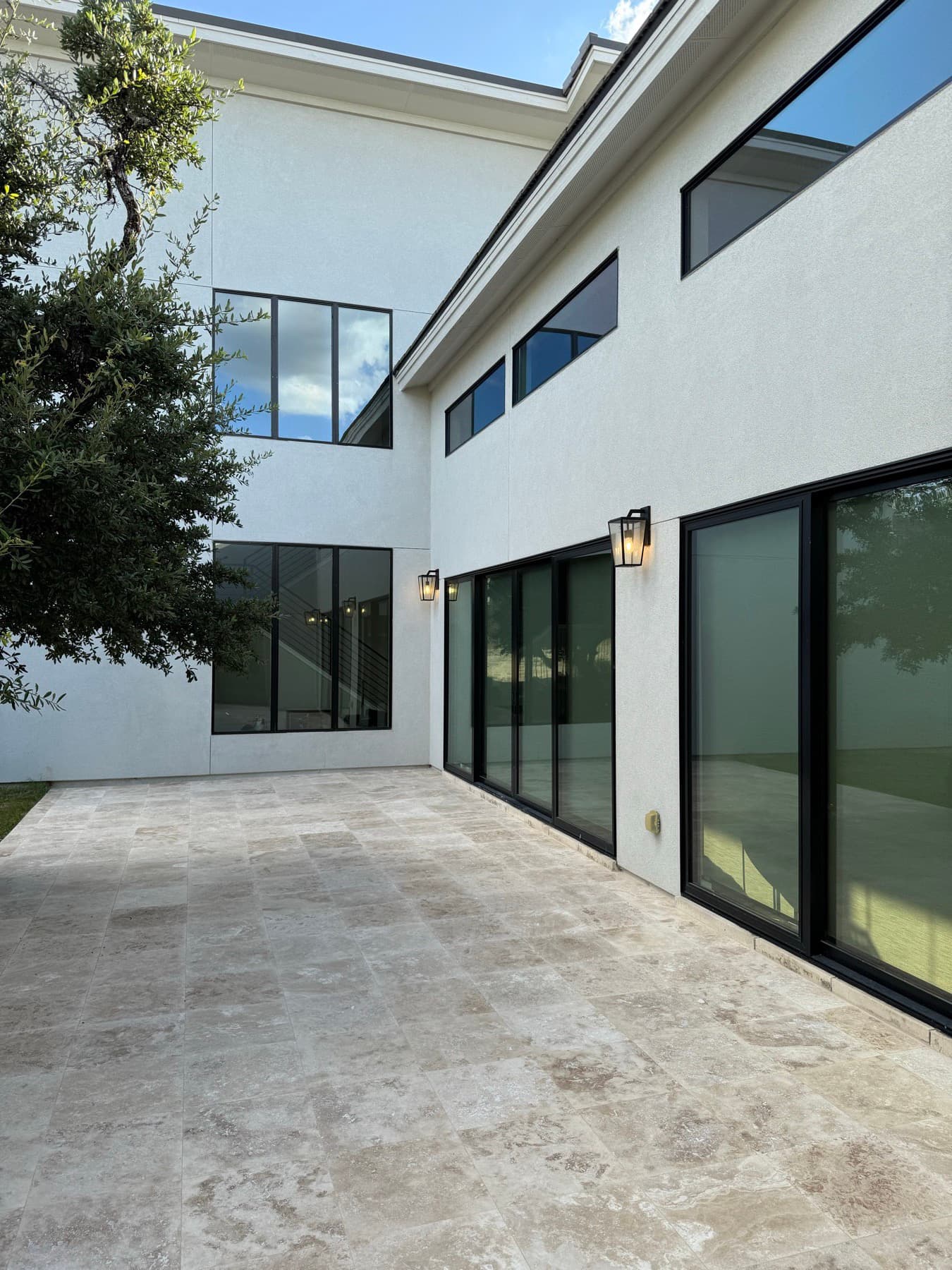 Travertine courtyard from the far side, the paving carried right up to the sliding doors and the planting edge.