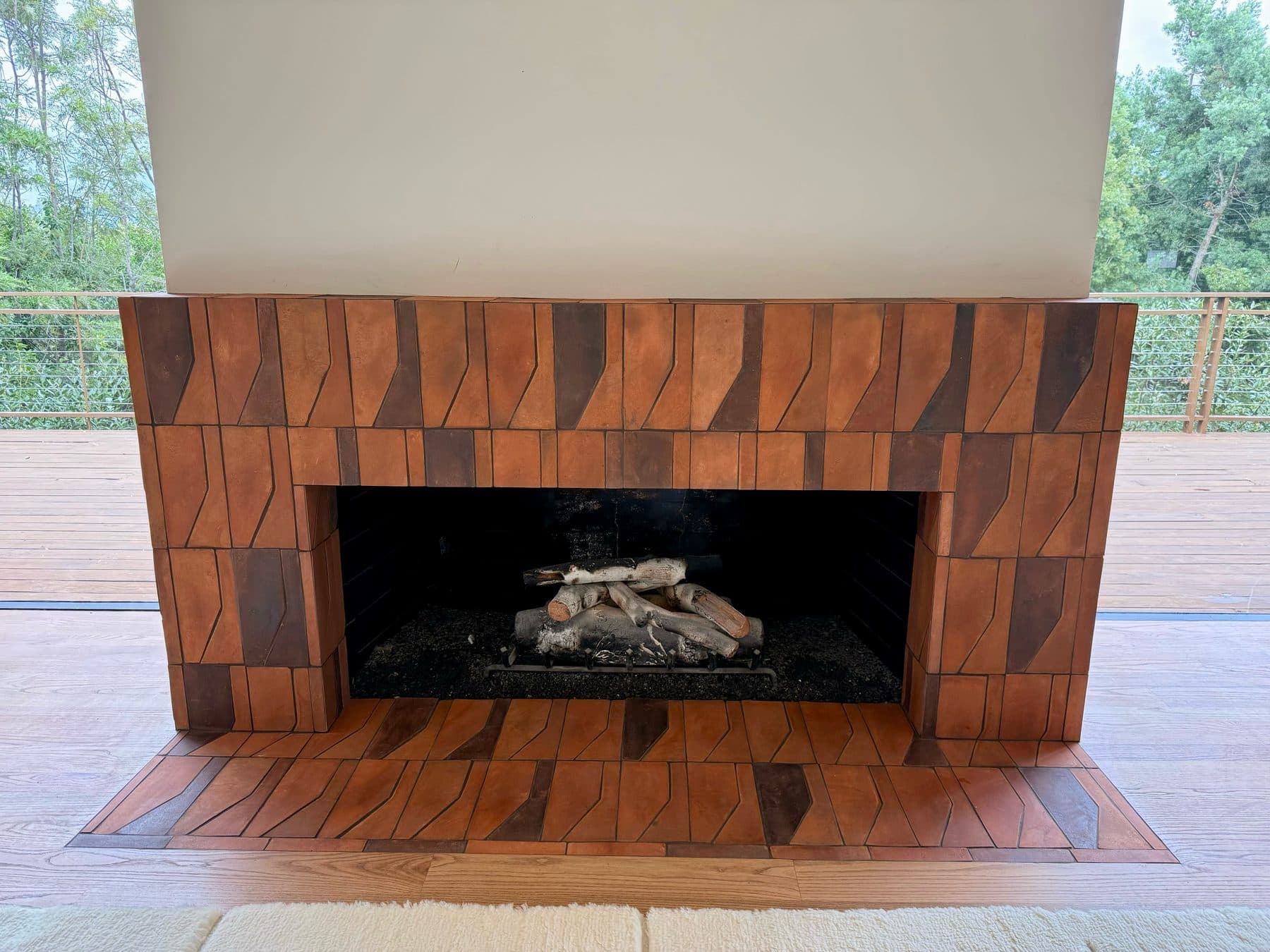 The fireplace from straight on: surround and hearth in handmade Zocalo terracotta, Red Clay and darker Madera tiles mixed through the pattern, with the deck and the Encino hills beyond.