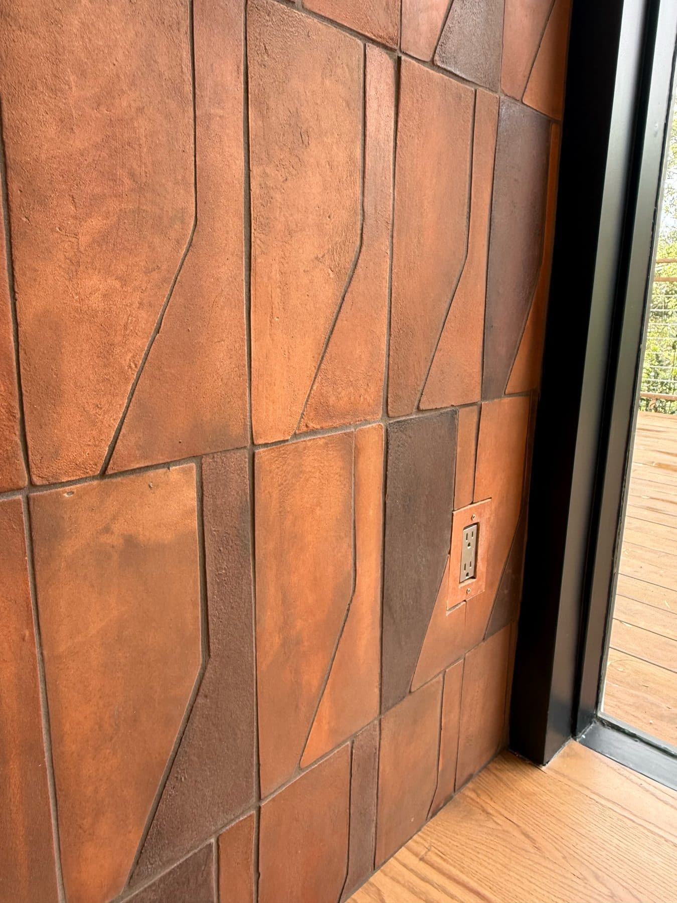 Close view of the handmade terracotta on the side of the surround, showing the wood-ash finish and an outlet cut into the tile.
