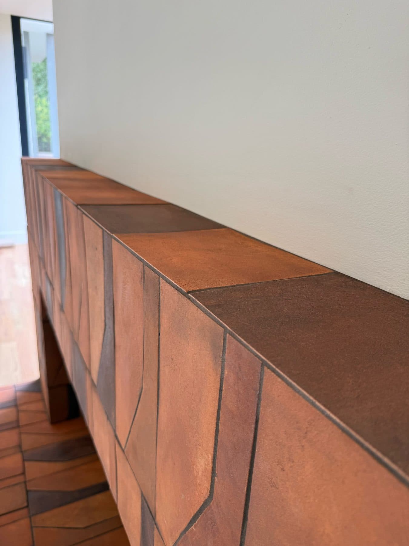 The top of the surround in plain 8×8 tile of the same finish and color, breaking up the pattern below it.