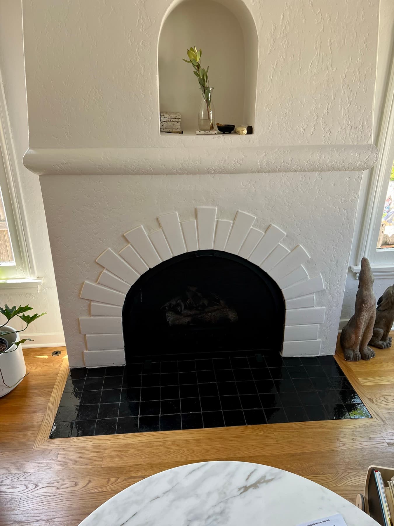 A Spanish-style fireplace in Highland Park with an arched white tile surround and a glossy black zellige hearth
