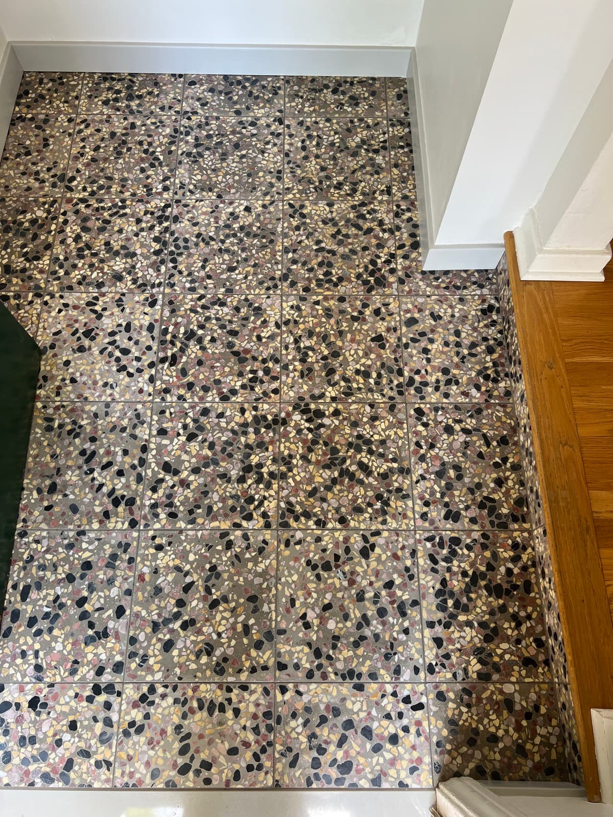 The entry landing from above, terrazzo running wall to wall to the base of the stairs.