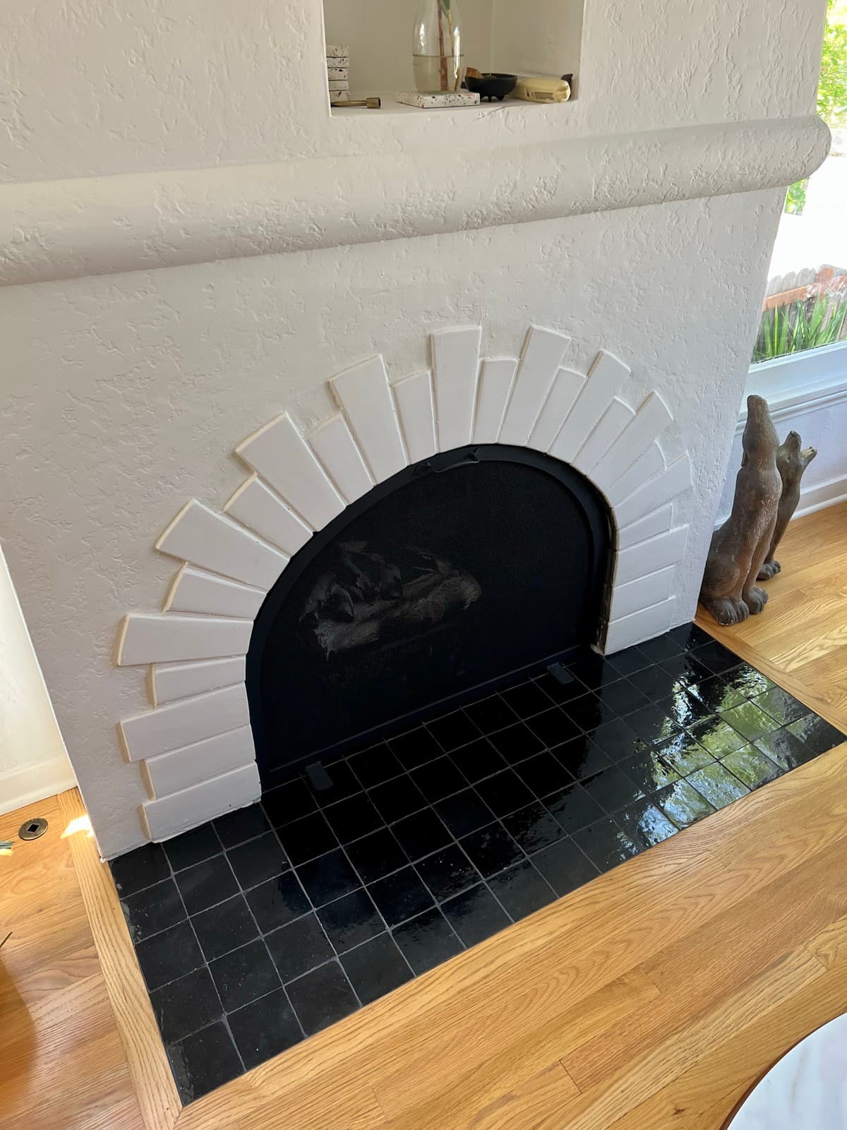 A Spanish-style fireplace in Highland Park with an arched white tile surround and a glossy black zellige hearth