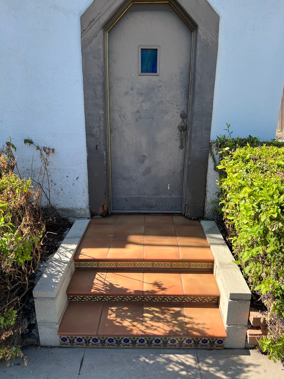 The same steps rebuilt on block and rebar and finished in 12×12 Saltillo treads with Malibu tile risers, the door still unpainted