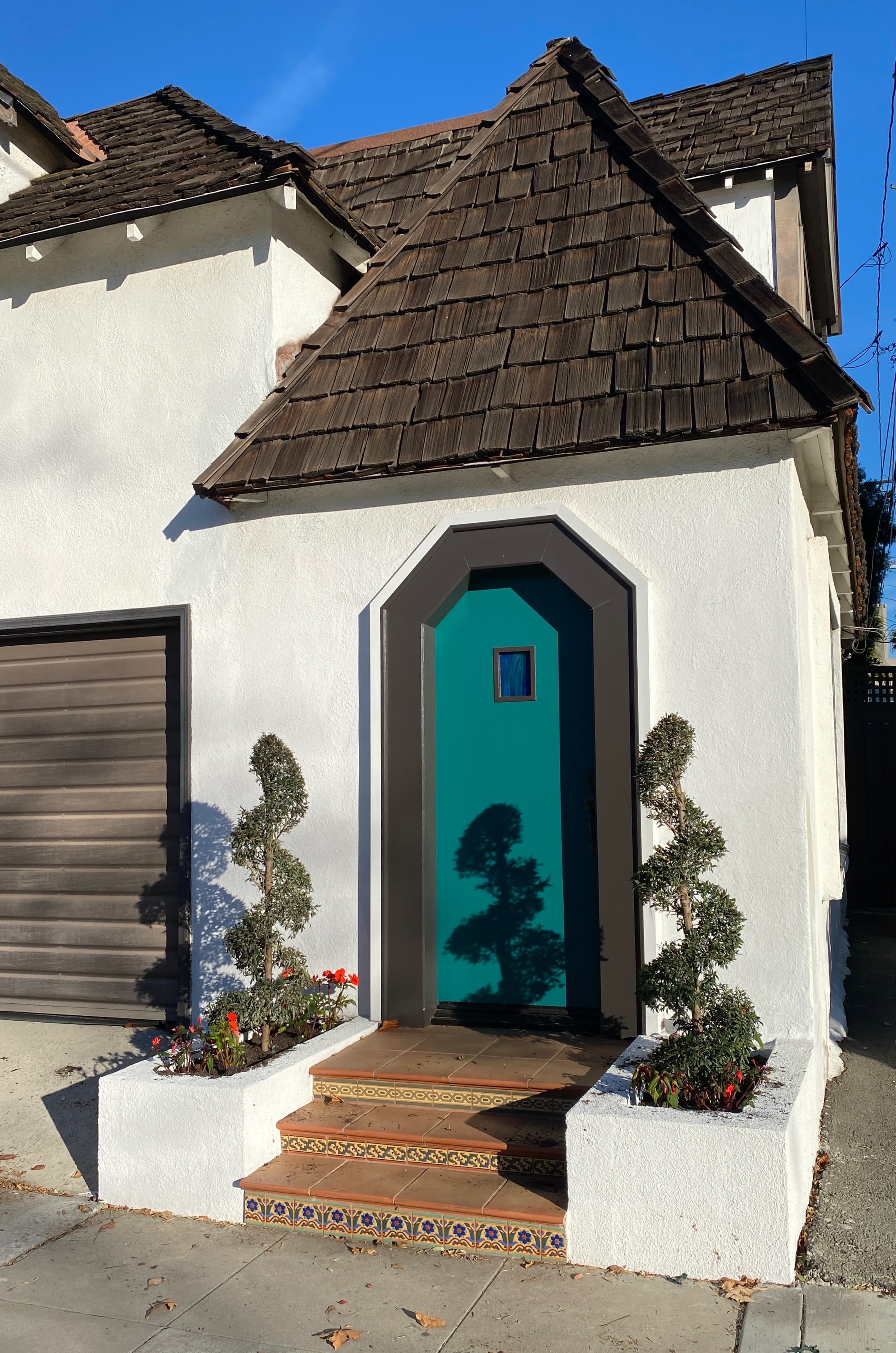 The finished side entry: the door painted deep teal, new planters built either side, and the tiled steps in full sun