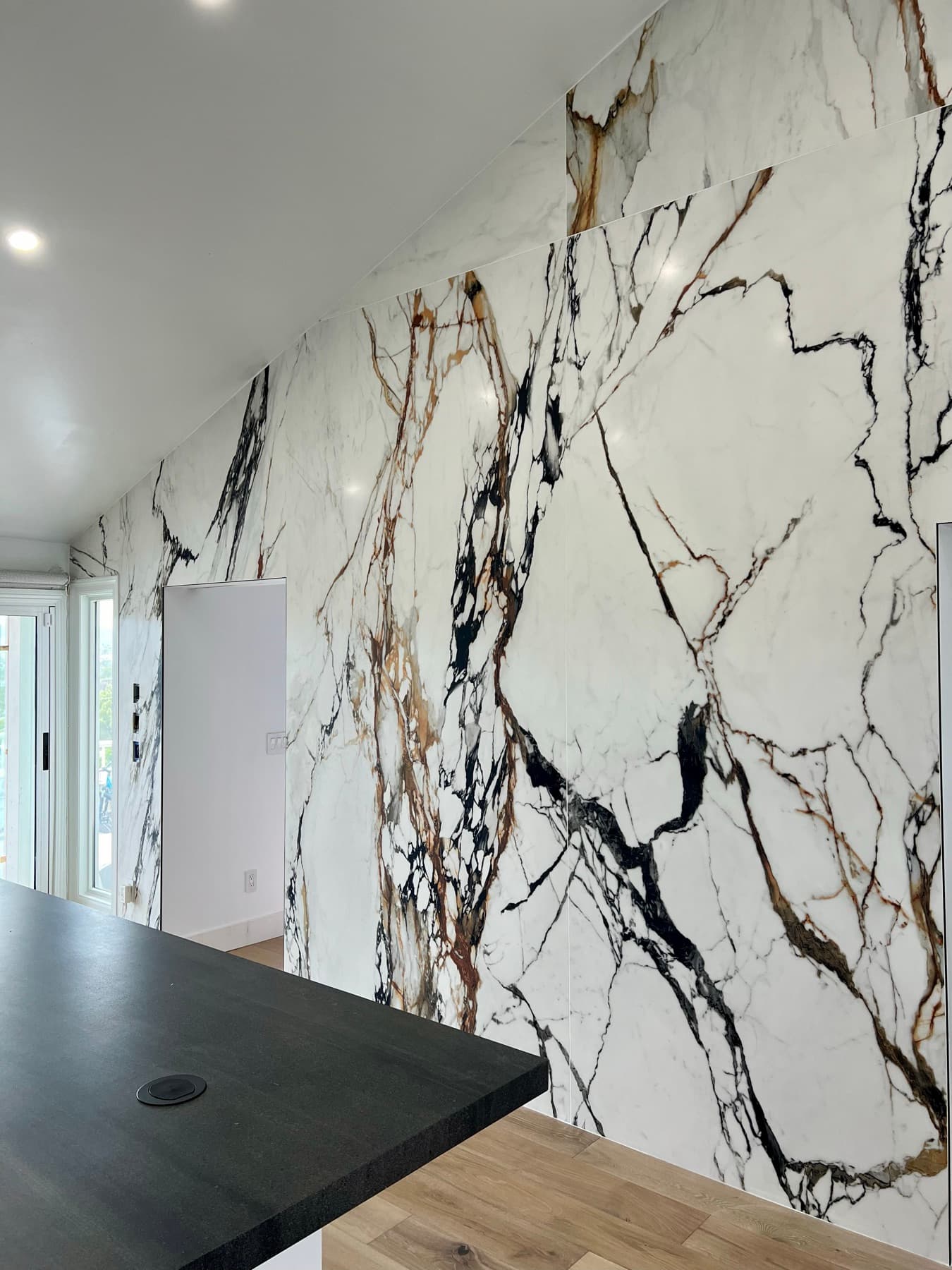 The bookmatched slabs wrapping an outside corner and running full height under the vaulted ceiling.