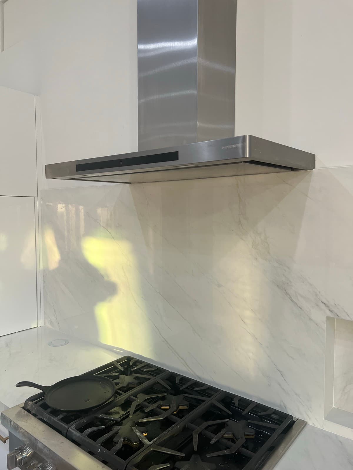 The right edge of the cooktop wall, where a mitered niche is cut into the backsplash slab for spices and utensils.