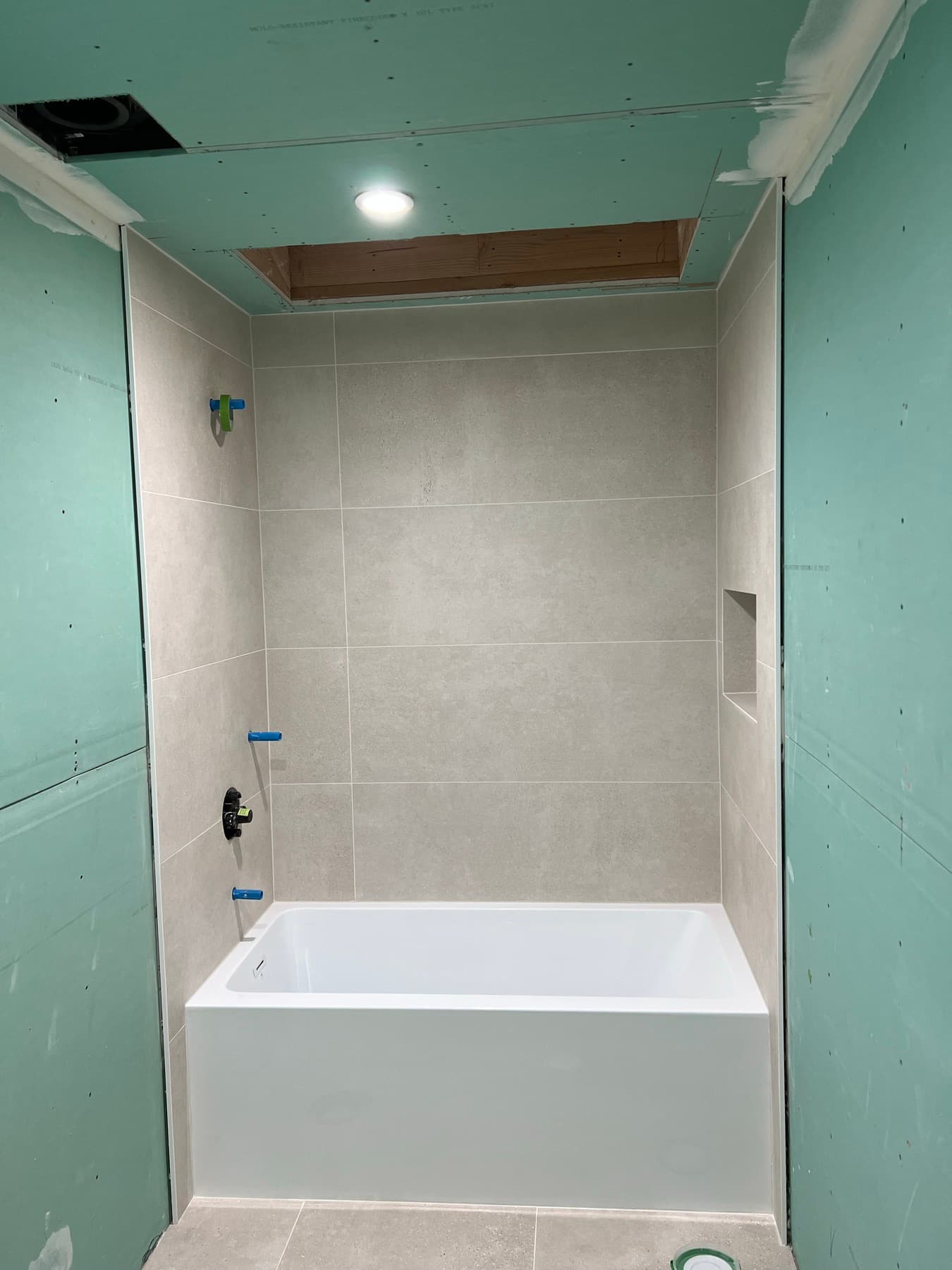 Mid-project: tub set and Porcelanosa walls tiled, skylight opening still framed in
