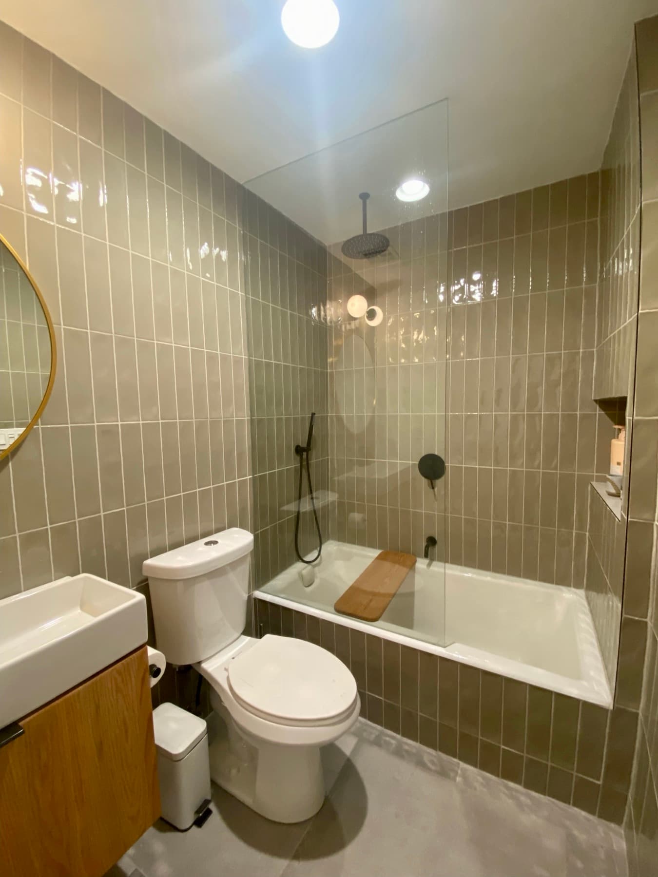 Sage green tile meeting a tub deck and brass fixtures in a Los Angeles bathroom